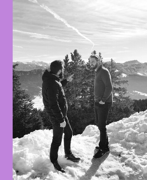 Damien et Rémi posent devant un paysage de montagnes enneigées